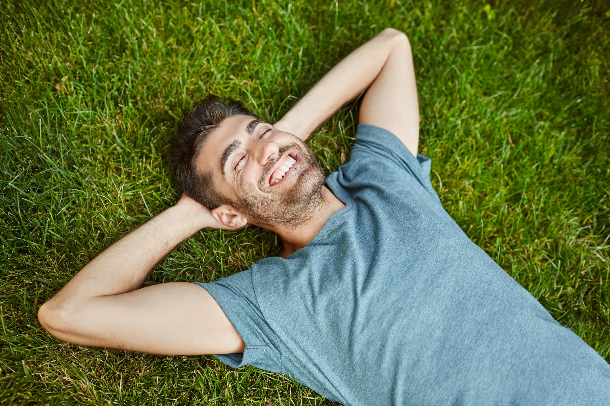 A man laying on the grass with his eyes closed not measuring pasture accurately