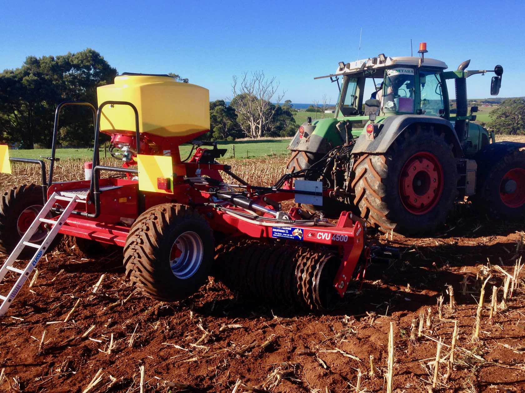 Tractor drilling grass seed into maize stubble.